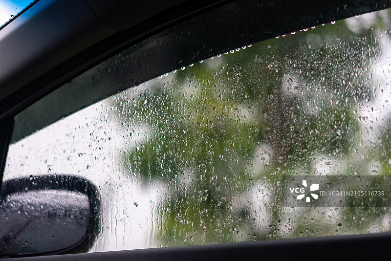 汽车窗户上的雨滴与模糊的窗外景色图片素材