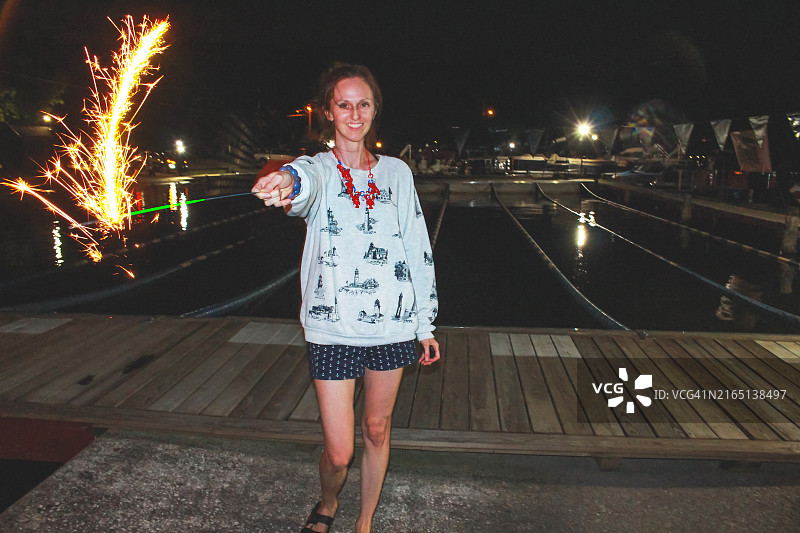 快乐的女人在7月4日拿着烟火棒，夏季度假图片素材