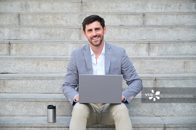 商务人士坐在城市台阶上工作，面带微笑图片素材