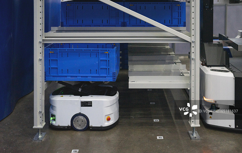 具有自动导向车搬运纸板箱的仓库内部图片素材