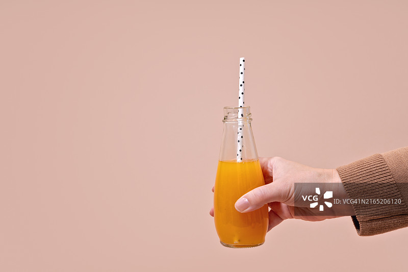 一手拿着一瓶橙色南瓜汁冰沙图片素材