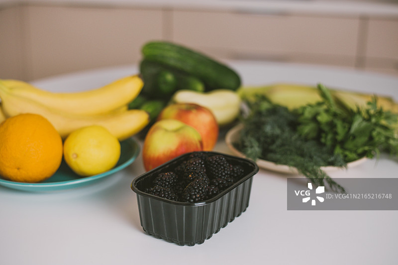 白色桌子上的黑莓、水果、蔬菜和绿色植物图片素材