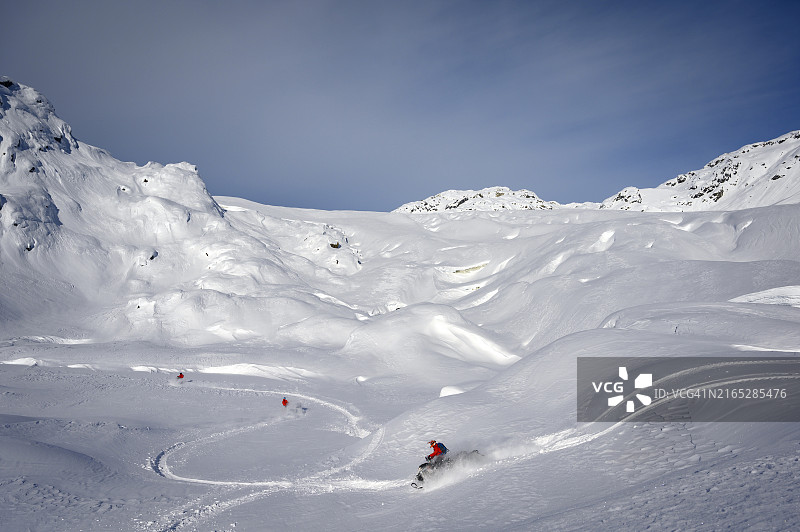 一群荒野雪地摩托车手在冰川上行驶图片素材