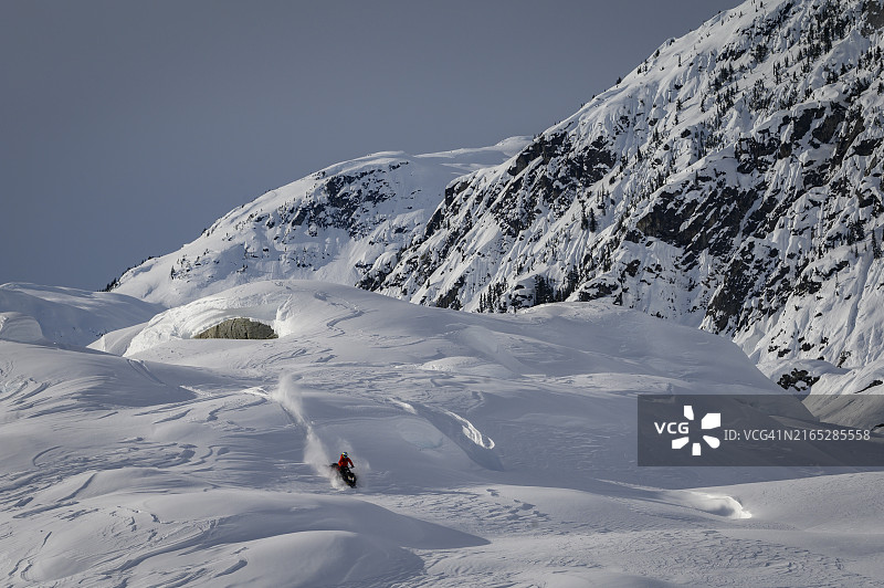 滑野雪的雪地摩托车手穿越冰川图片素材