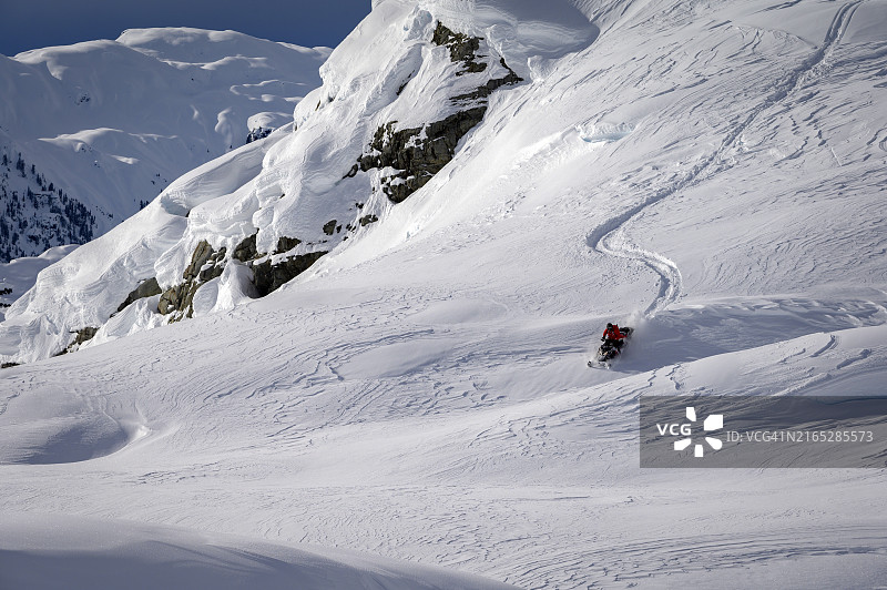 滑野雪的雪地摩托车手穿越冰川图片素材