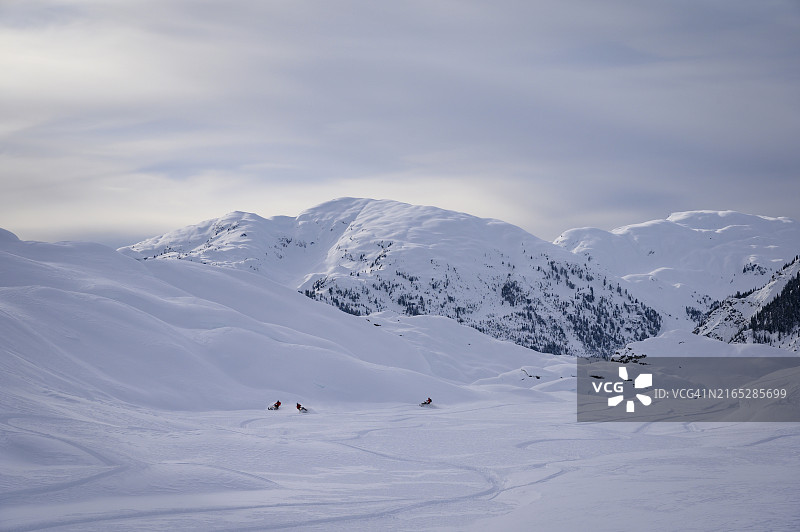 一群荒野雪地摩托车手在冰川上行驶图片素材