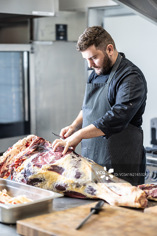 肉店里，屠夫从一头公牛身上切下一大块完整的后腿图片素材