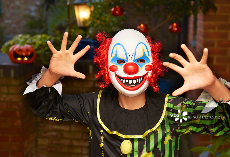 戴着小丑面具吓唬人的小男孩图片素材