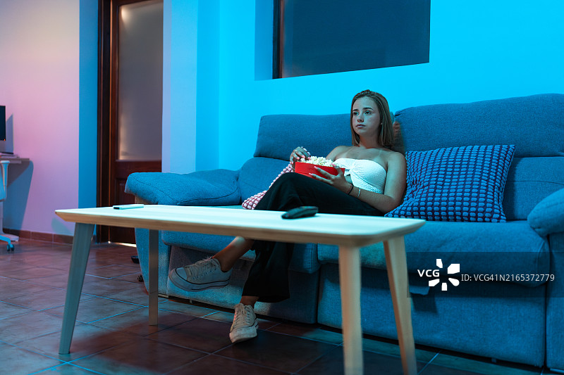 年轻女子在家享受爆米花电影之夜图片素材