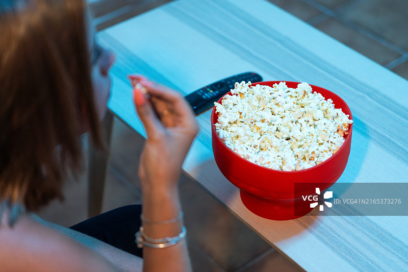 和爆米花一起享受电影之夜的年轻女人图片素材