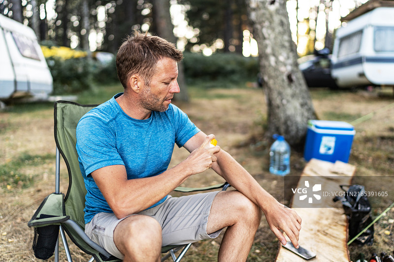 男人在露营时使用喷雾进行防护图片素材