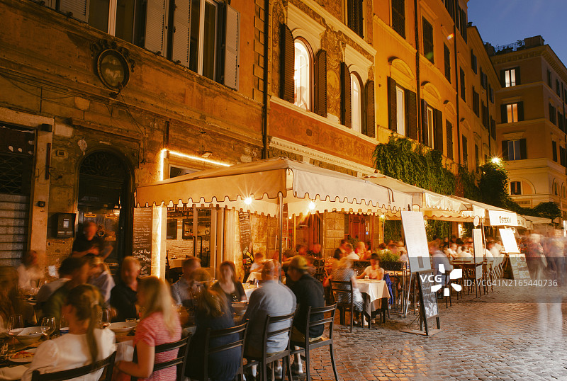 夜晚，罗马繁忙街道上的人们在餐厅和酒吧外用餐图片素材