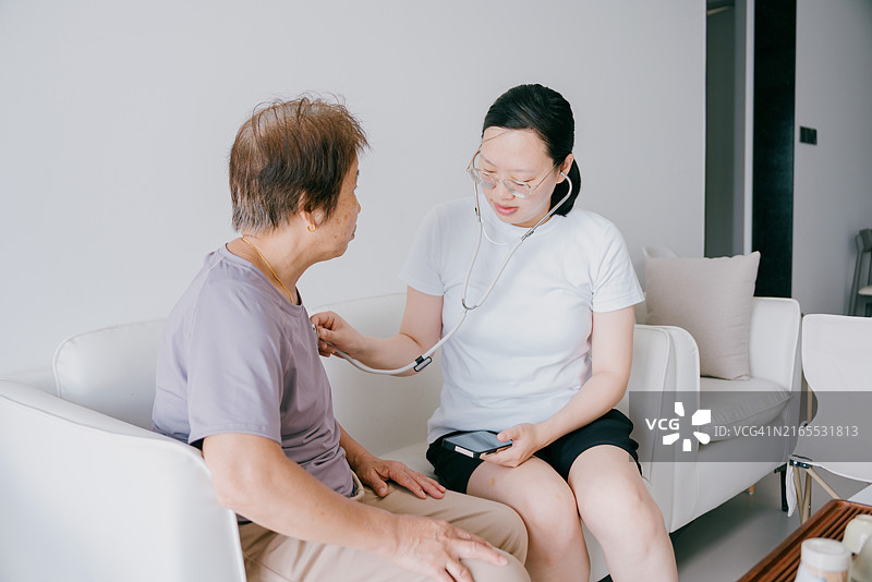 亚洲女性在家使用听诊器为母亲检查图片素材