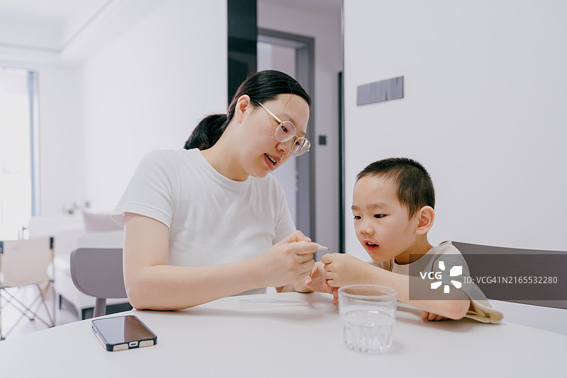 亚洲母亲在家用体温计给儿子量体温图片素材