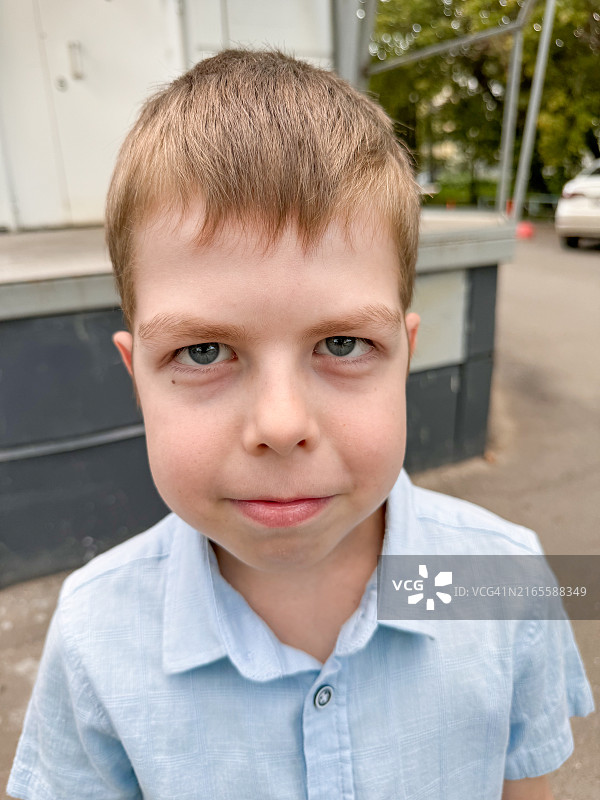 蓝眼睛的金发小男孩看着镜头，天真可爱的孩子图片素材