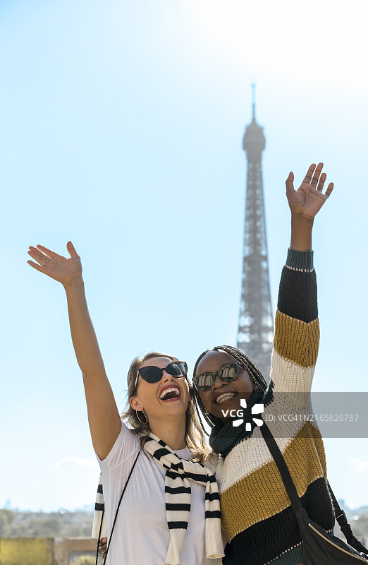 在巴黎度假的年轻快乐的多种族女友举手仰望天空图片素材