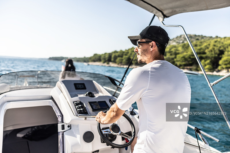 戴太阳镜驾驶游艇的男人图片素材