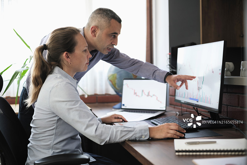 商务人士在办公室使用台式电脑和数位板处理股票市场交易所数据图片素材