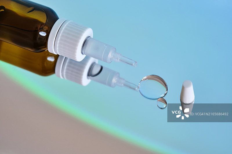 镜面蓝色背景上的滴耳液瓶图片素材