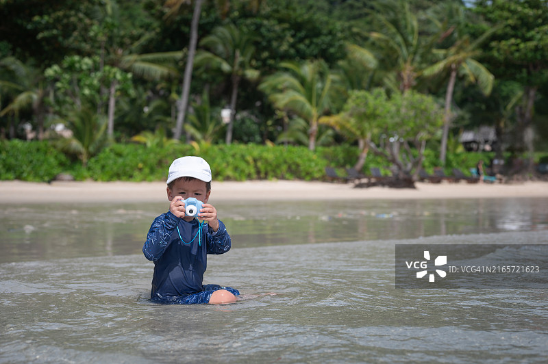 在泰国海滩上玩相机的小男孩图片素材