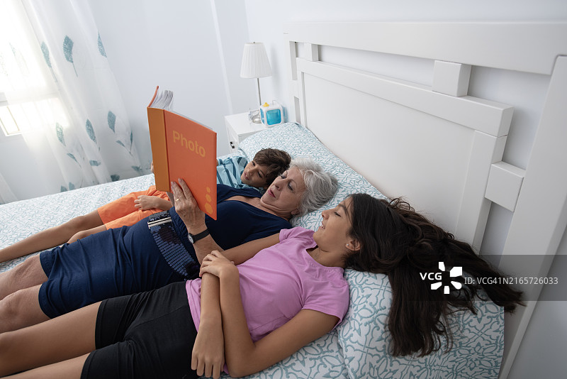 奶奶在床上给孙子孙女看照片图片素材