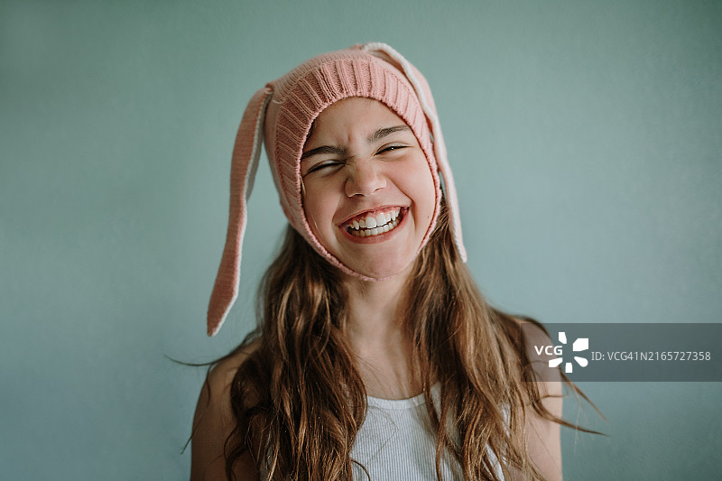 戴着兔子帽，闭着眼睛，开怀大笑的年轻女孩肖像图片素材