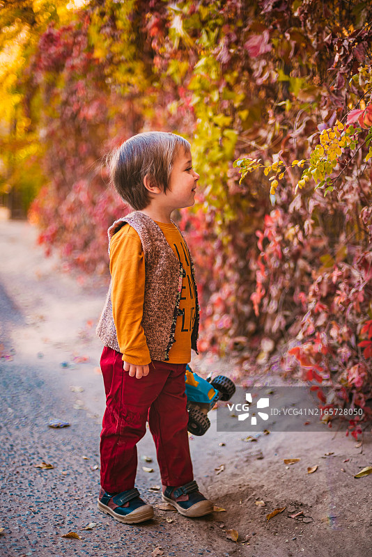 哈萨克斯坦，站在树丛中的道路上的男孩侧面照图片素材