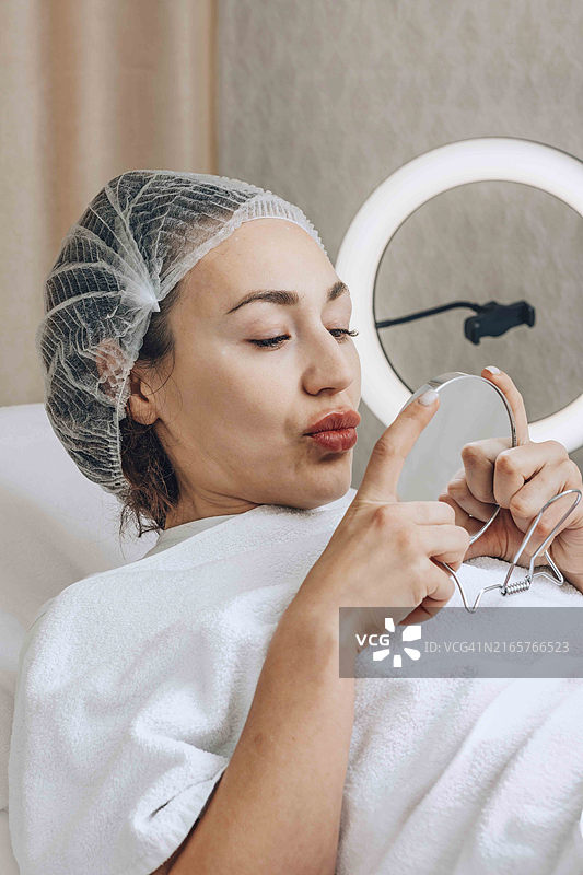 女子仔细观察最新护肤品的效果图片素材