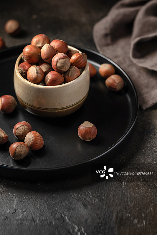 深色纹理背景碗中的榛子，留有文本空间，素食图片素材