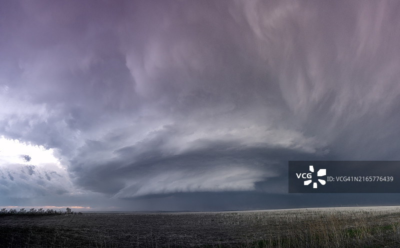 黄昏时分广阔田野上空的戏剧性风暴云，地平线上有一线阳光图片素材