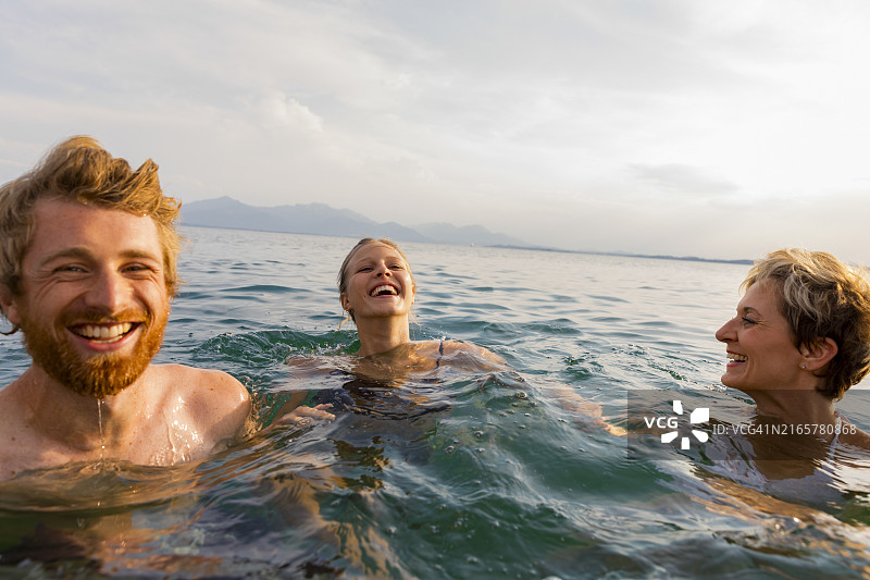 三个人在清澈的天空下一起游泳欢笑图片素材