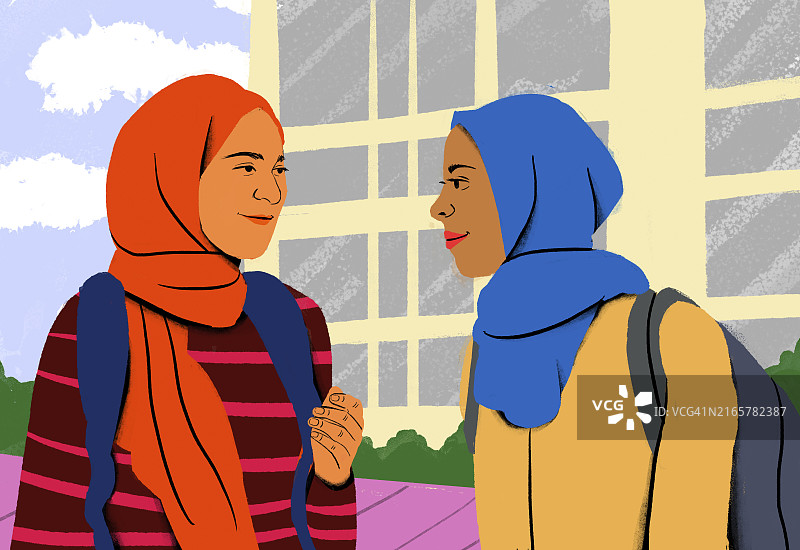 两个戴着头巾和背包的微笑女人在建筑物前友好交谈图片素材