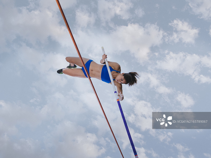 女运动员在多云的天空背景下跳过高杆图片素材