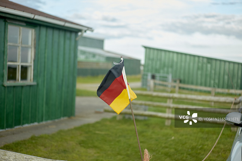 乡村环境中绿色木制建筑前的德国国旗图片素材