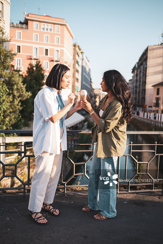 在意大利米兰户外享用冰淇淋的两个朋友图片素材