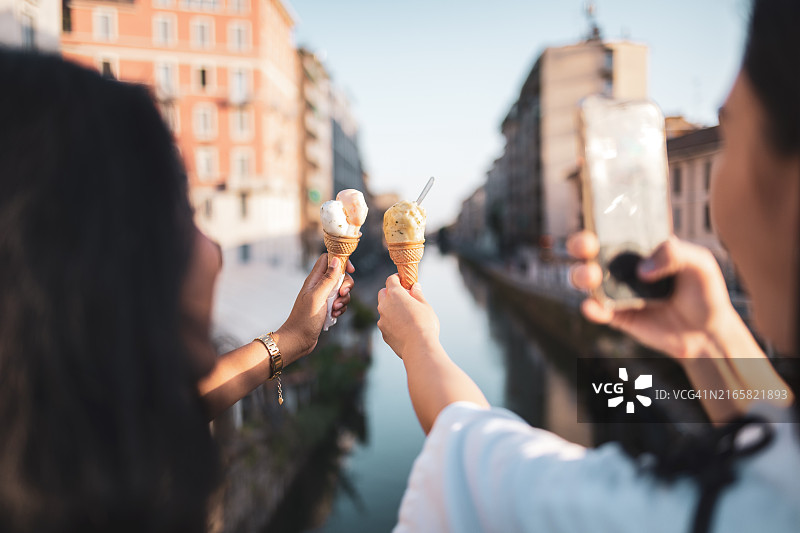 两位朋友在意大利米兰的运河附近享用冰淇淋图片素材