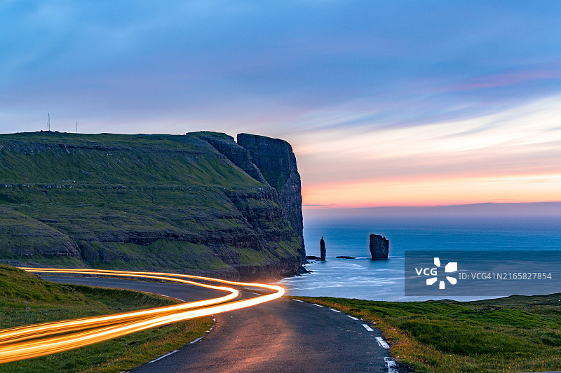 黄昏时海洋沿岸公路上的汽车光轨图片素材