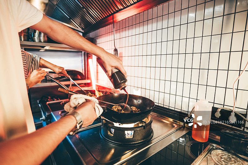中餐馆：厨师在霓虹灯餐厅烹饪食物图片素材