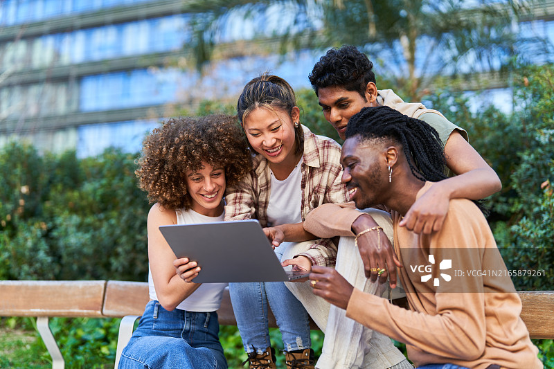 一群年轻人在公园里一起使用笔记本电脑，玩得很开心图片素材