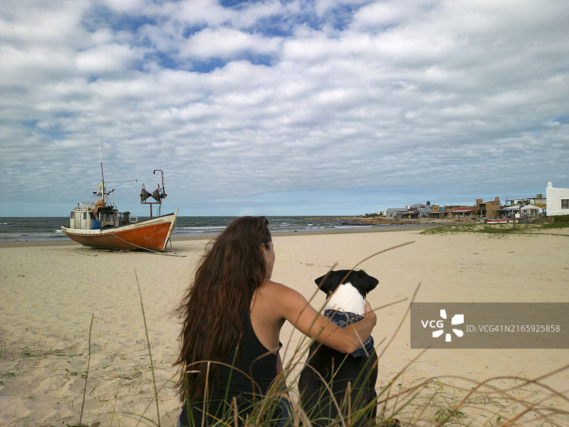 在海滩上与狗玩耍的女人图片素材