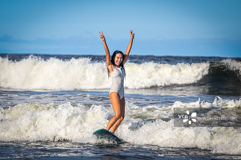 一位漂亮女人在冲浪板上做V字手势图片素材