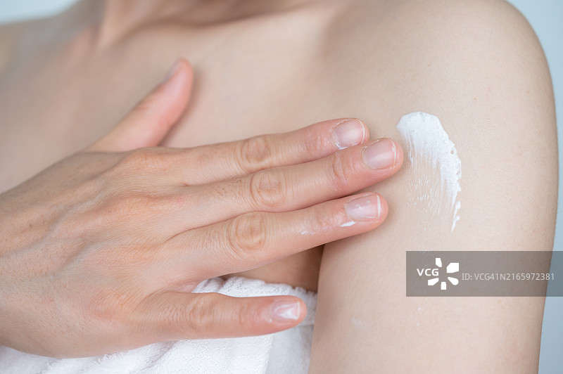 亚洲女人在肩膀上涂抹润肤霜的特写镜头图片素材