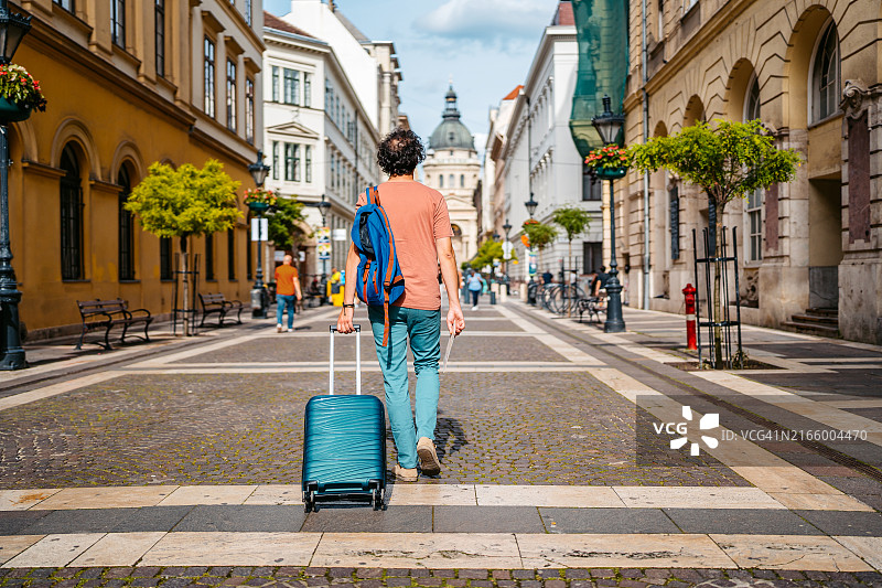 中年男人在匈牙利布达佩斯街头搬运行李的背面视角图片素材