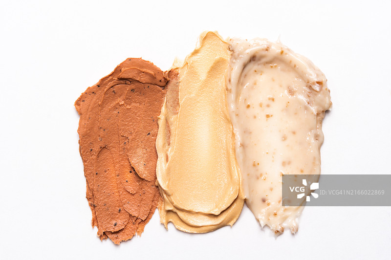 白色背景上的化妆品涂抹痕迹：保湿霜、洁面面膜、沐浴露、去角质磨砂膏和护发素，含肽、益生元、神经酰胺、壬二酸等成分图片素材