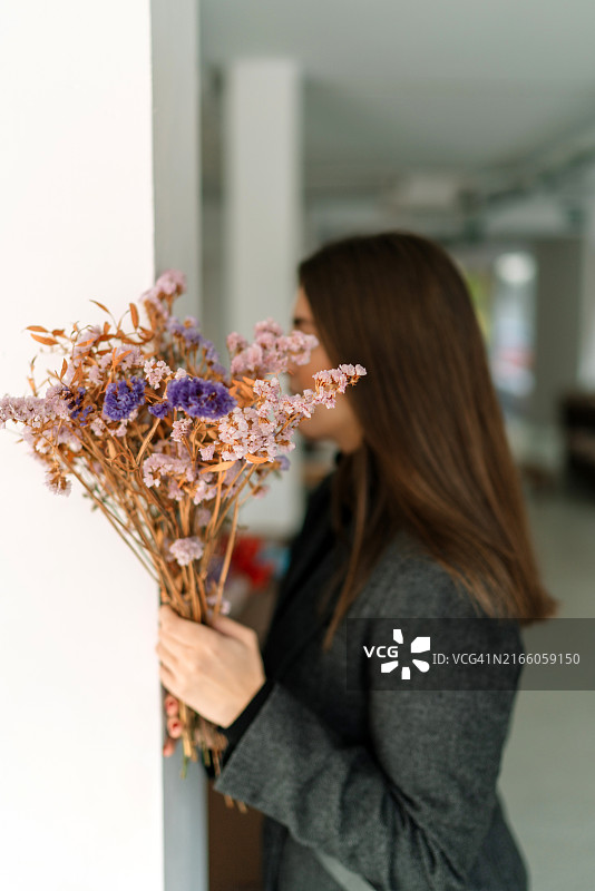 靠墙站立的持花女子图片素材