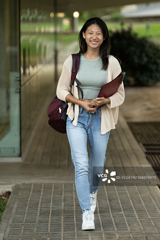 满意的男学生拿着笔记本在户外行走图片素材