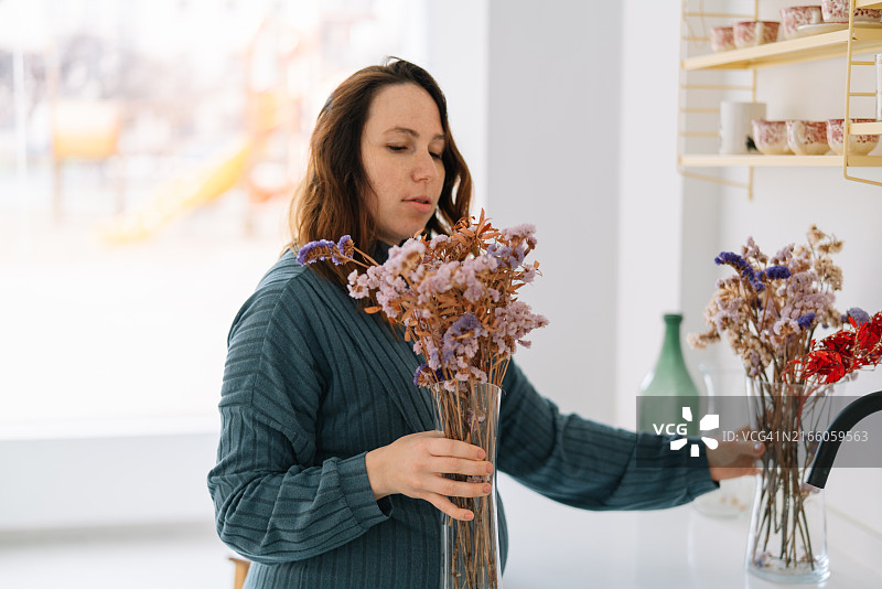孕妇闻着花瓶里的花图片素材