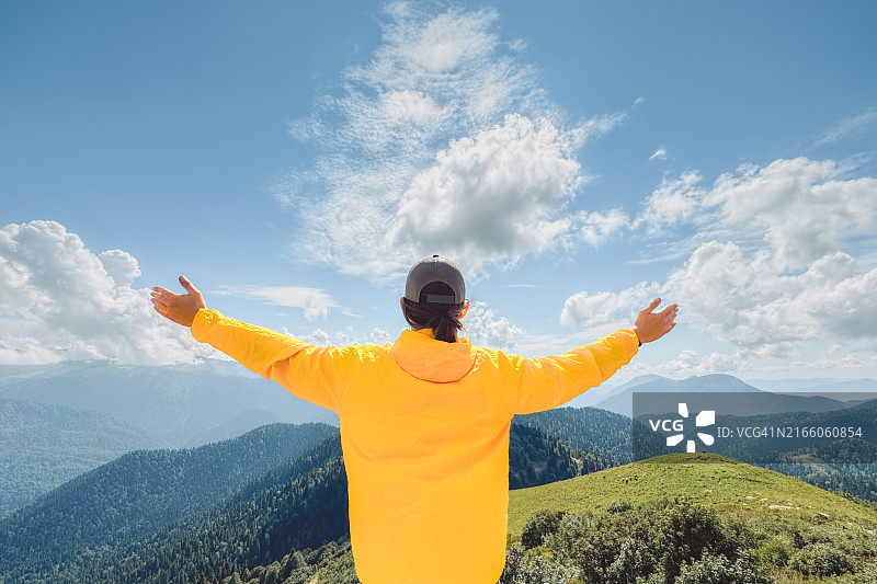 举起双臂，欣赏如画山景的男人图片素材