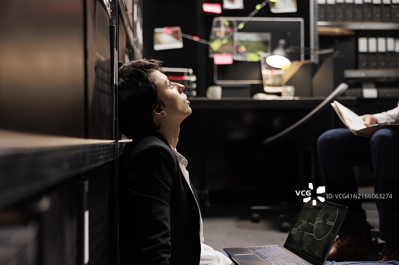 私家侦探在黑暗的办公室里查看监控照片和调查文件图片素材