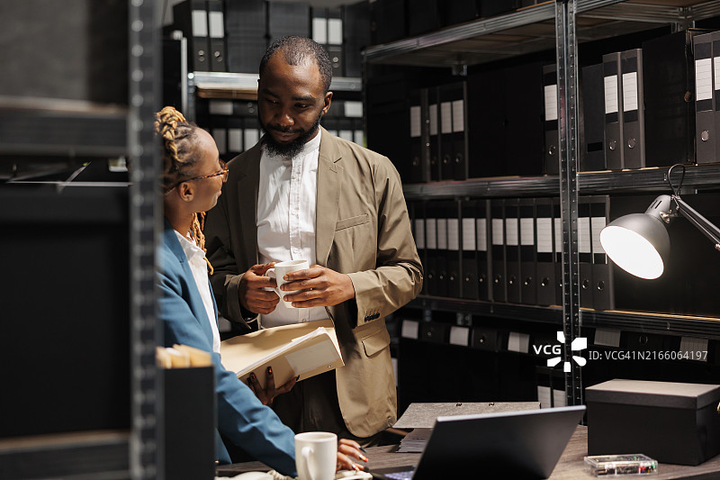 私家侦探在黑暗的办公室里查看监控照片和调查文件图片素材